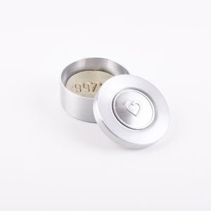Een crematie steen doosje, in ronde uitvoering van aluminium. Zilverkleurig met een deksel waarin een mooi hartje is verwerkt. Voor het bewaren van heel speciale items.