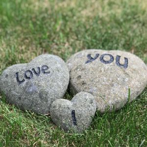 Een tekst gegraveerd in drie natuurstenen harten in verschillende grootte. I Love you, op elk hart een woord. Liefdevolle decoratie.