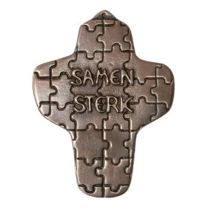 Samen sterk, een bronzen kruisje met als achtergrond puzzelstukjes. De tekst samen sterk is in reliëf gegoten en daarom ook voelbaar, evenals de randen van de puzzelstukjes. Mooi geschenk voor Communie, doop of vormsel.