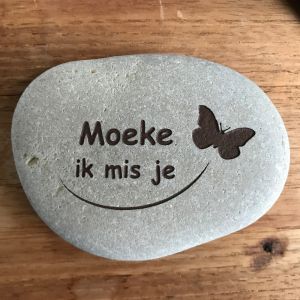 Een gedenksteentje met vlinder. Moeke ik mis je als diepe gravure in een wit-grijs steentje, zwart ingekleurd.