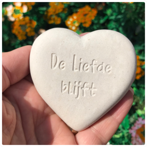 Een diepe gravure van de tekst: de liefde blijft, in een wit natuurstenen hart. Een zielsgeschenk, cadeautje vanuit je hart. 