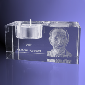 Een kristallen rechthoek met een uitsparing om een kaarsje in te branden en een 3d lasergravure van een door u aangeleverde foto, in dit geval een portret van een man. Met zijn naam en data ook in lasergravure toegevoegd onder het kaarsje.
